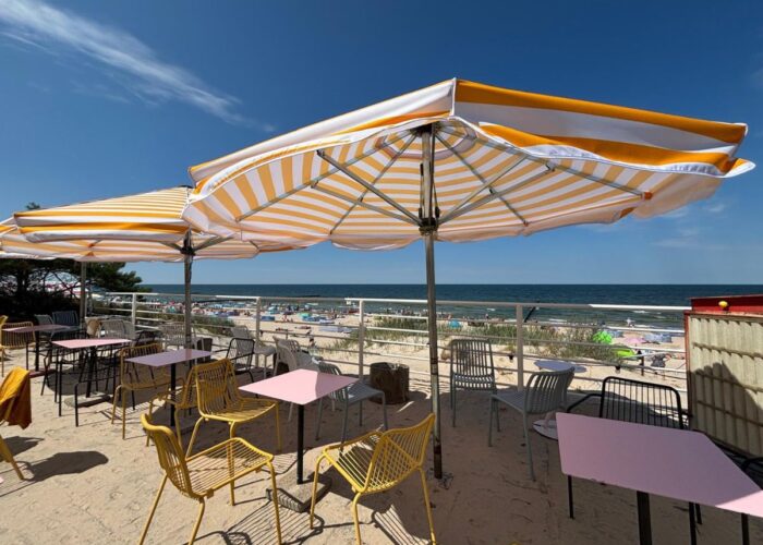 Sonnenschirme und Sitzplätze auf einer Terrasse mit Blick auf die Ostsee.