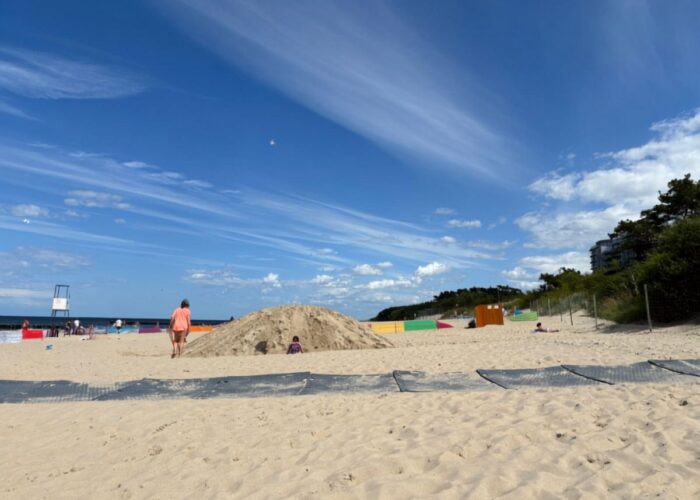 Breiter Sandstrand in Dziwnówek unter blauem Himmel.