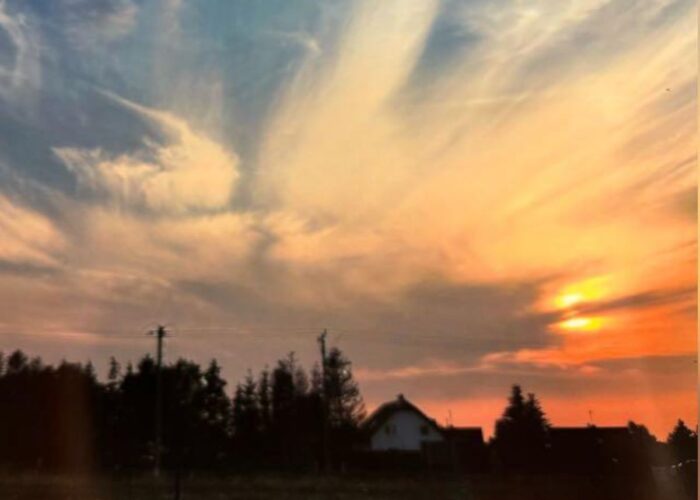 Sonnenuntergang mit leuchtenden Wolken über den Dächern von Dziwnówek.