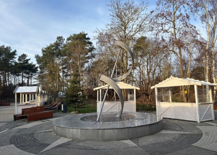Kleine Pavillons und Sitzbereiche auf einem Platz zwischen Bäumen.