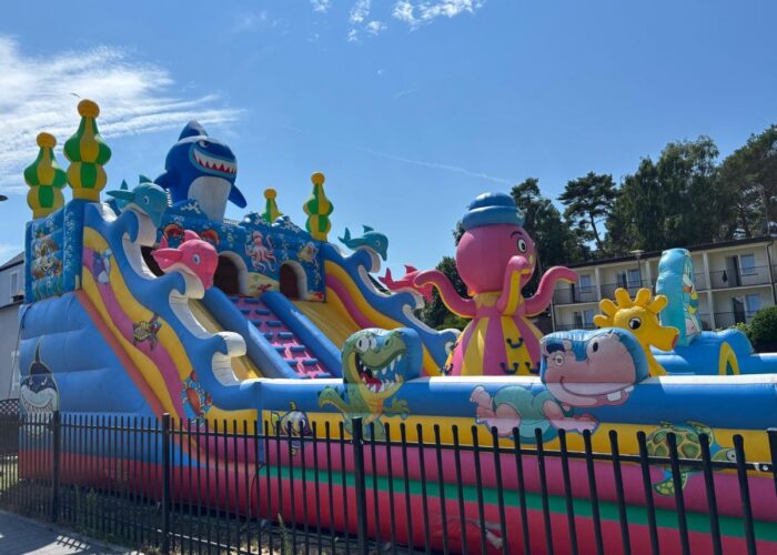 Bunte Hüpfburg mit Rutschen in einem Freizeitpark.