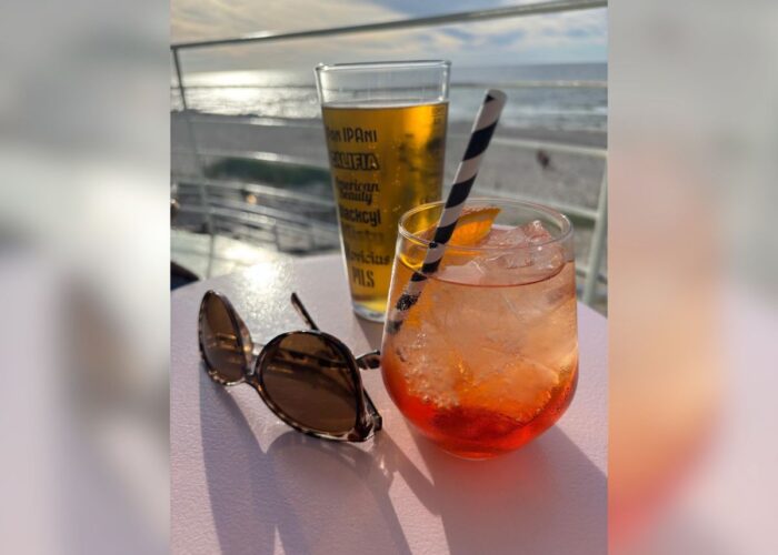 Zwei Getränke und eine Sonnenbrille auf einem Tisch mit Blick auf die Ostsee.