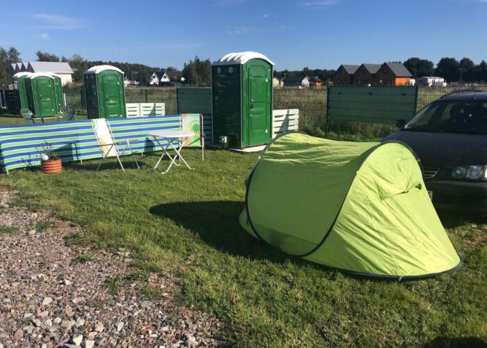 Zelt auf einem Stellplatz mit eigener grüner WC-Kabine auf dem Campingplatz.