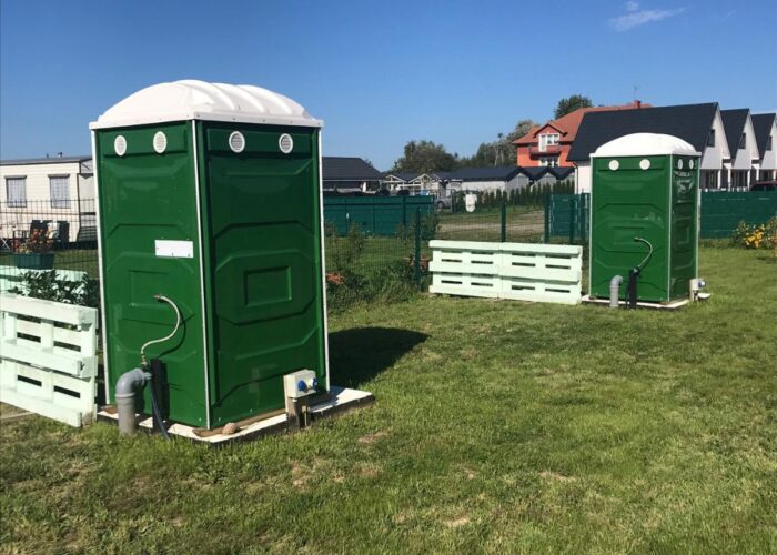 Zwei grüne WC-Kabinen auf den Stellplätzen des Campingplatzes.