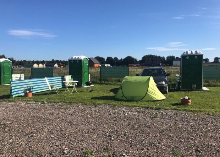 Zelt und grüne WC-Kabinen auf den Stellplätzen des Campingplatzes.